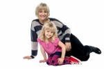 Cheerful Mum And Daughter Sitting On Studio Floor Stock Photo