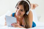 Beautiful Girl Listening To Music With Tablet On Sofa At Home Stock Photo