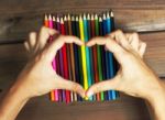 Female Hands In The Shape Of A Heart On Colored Pencils On A Bac Stock Photo