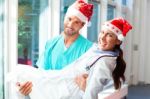 Happy Surgeon Carrying Female Doctor During Christmas Stock Photo