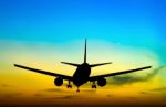 Silhouetted Commercial Airplane Flying At Sunset Stock Photo