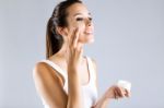 Pretty Young Woman Applying Body Cream. Isolated On Gray Backgro Stock Photo