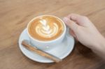 Hand On Hot Cup Of Coffee Latte Stock Photo