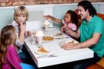 Cheerful Family Of Four Enjoying Breakfast Stock Photo