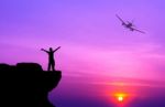 Silhouette Of A Man On The Rock And Silhouette Commercial Plane Stock Photo