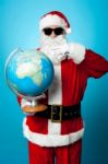 Stylish Santa In Dark Shades Pointing At The Globe Stock Photo