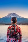 Asian Woman Wearing Japanese Traditional Kimono At Fuji Mountain. Sunset At Kawaguchiko Lake In Japan Stock Photo