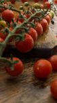 Cherry Tomatoes On Display On Wooden Chopping Board And Wooden Table Stock Photo