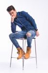 Male Model In Denim Jeans Sitting On A Chair . Studio Shoot Stock Photo