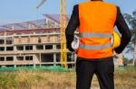 Young Engineer Wearing Orange Shirt Stands Holding A Hat And A B Stock Photo