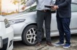 Insurance Agent Writing On Clipboard While Examining Car After A Stock Photo