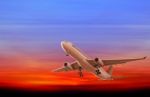 Commercial Airplane Flying At Sunset Stock Photo