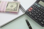 Stack Of Bank Note And Pen Calculater On Note Book Stock Photo