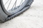 Bicycle Wheel With Flat Tyre On The Concrete Road Stock Photo