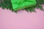 Green Gift With Polka Dot Ribbon And Cypress Leaf On Pink Background Stock Photo