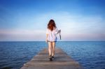 Woman Walking On Wooden Bridge Extended Into The Sea Stock Photo