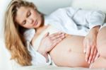 Young Pregnant Woman Resting On Sofa Stock Photo