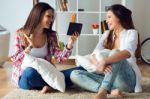 Two Beautiful Young Woman Friends Using Digital Tablet At Home Stock Photo