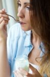 Young Woman At Home Eating Yogurt Stock Photo