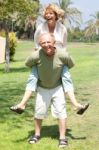 Image Of Senior Man Giving Woman Piggyback Ride Stock Photo