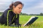 Dutch Woman Lying In Grass Reading Book Stock Photo