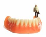 Miniature Elderly Standing On Removable Denture, On White Background. Dental Health Concept Stock Photo