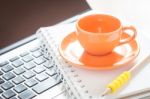 Laptop With Coffee Cup And Notepad On Desk Stock Photo