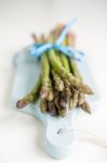 Bunch Of Fresh Asparagus On A Blue Wooden Cutting Board Stock Photo