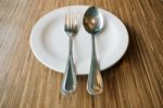 Empty Plate With Spoon And Fork On Wooden Stock Photo