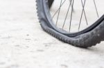 Bicycle Wheel With Flat Tyre On The Concrete Road Stock Photo