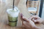 Woman Hand Holding Phone With Background Of Iced Green Tea Stock Photo