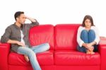 Unhappy Young Couple Sitting On Red Sofa Stock Photo