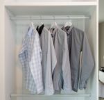 Row Of Shirts Hanging In White Wardrobe Stock Photo