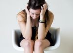 Depressed Young Woman Sitting At Home Stock Photo