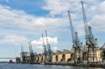 Old Dockside Cranes Alongside A Waterfront Development Stock Photo