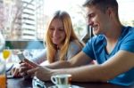 Group Of Friends Using Mobile Phone In Cafe Stock Photo