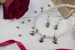 Pearl Necklace With Golden Gift, Red Rose And Rd Ribbon On White Wood Stock Photo