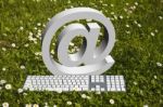 Keyboard With At In Daisy Garden Stock Photo