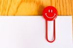 Close Up Of A  Red Paper Clip And White Paper On Wood Table Stock Photo