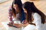 Two Beautiful Young Woman Friends Using Digital Tablet At Home Stock Photo