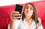 Young Woman Puckering While Taking Selfie On Sofa Stock Photo