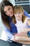 Mother And Daughter Using Laptop In The Kitchen Stock Photo