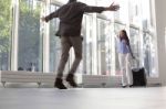 Woman With Luggage Waving To Boyfriend At Airport Stock Photo