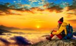 Young Woman Sitting On The Hill Of High Mountains At Sunrise Stock Photo