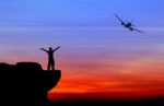 Silhouette Of A Man On The Rock And Silhouette Commercial Plane Stock Photo