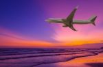 Commercial Airplane Flying Above The Sea At Sunset Stock Photo