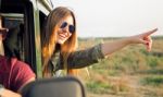 Portrait Of Beautiful Girl On Car Roadtrip Pointing Forward Stock Photo