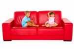 Brother And Sister On Red Sofa Stock Photo