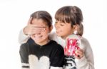 Little Girl Giving Surprise Love Gift To Her Friend With White Background Stock Photo