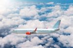 Airplane Flying Above Clouds In Sunlight Stock Photo